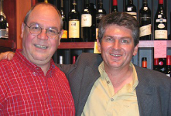 Bob Monica in a red collared shirt standing to the left of Neil Pike who is wearing a dark gray blazer and cream colored collared shirt.
