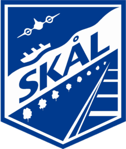 A logo with the image of a plane, boat, and railroad tracks and the text Skal in the middle.