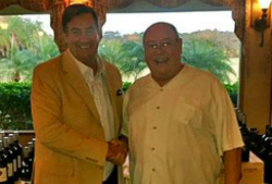 Tim Boydell wearing a yellow blazer and yellow collared shirt standing on the left side of Bob Monica who is also wearing a yellow collared shirt.