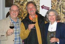 Bob Monica (left), Tino Colla (center), and a woman (right) stand while all holding a glass of wine.