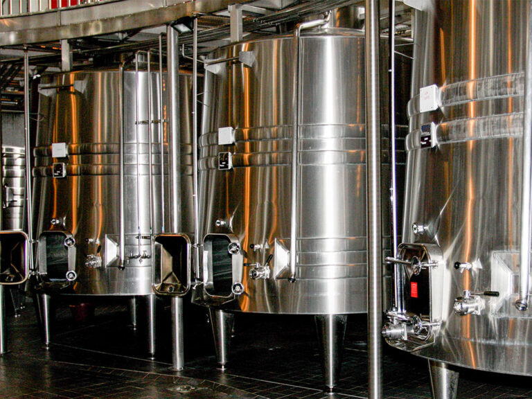 Large stainless steel tanks standing together in a room.